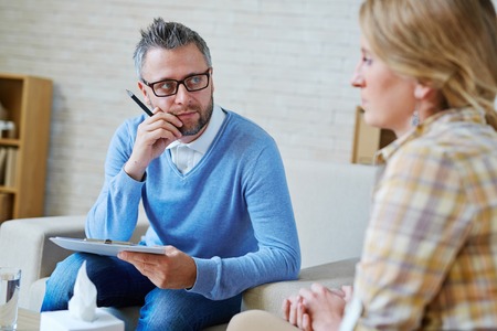 Mature psychologist listening to his patientの写真素材