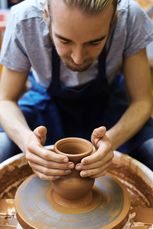 Young potter making clay jug in his workshopの写真素材