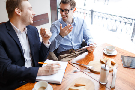 Young traders communicating in cafe at lunch or coffee breakの写真素材