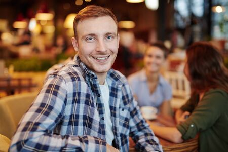 Cheerful young man looking at camera against his friendsの写真素材