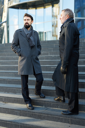 Young and mature economists standing on stairsの写真素材