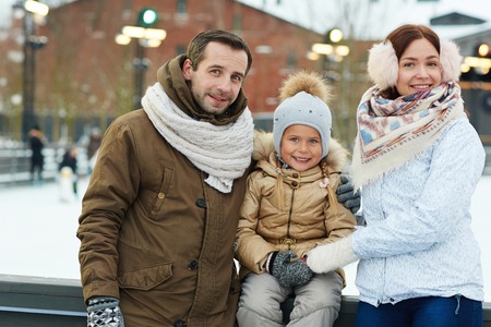 Active family of three spending weekend on skating-rinkの写真素材