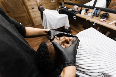 Barber in protective gloves massaging face of his clientの写真素材