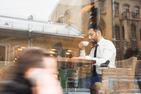 Businessman with cup of coffee networking in cafeの写真素材