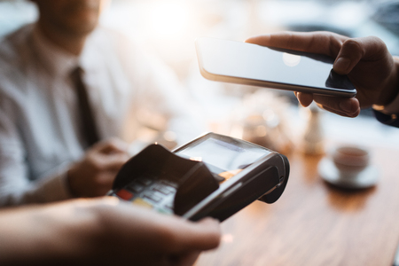 Buyer with smartphone paying through terminalの写真素材