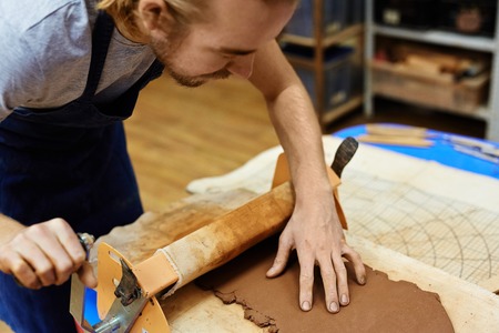Young potter expanding clay in workshopの写真素材