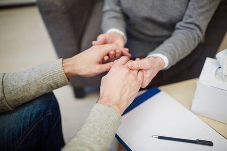 Hands of psychologist and patient in trouble during prayの写真素材