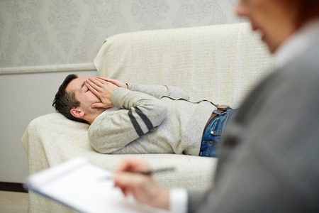 Frustrated man lying on couch while visiting counselorの写真素材