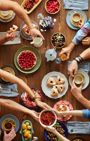Human hands over xmas table with fresh dessert, turnovers and berriesの写真素材