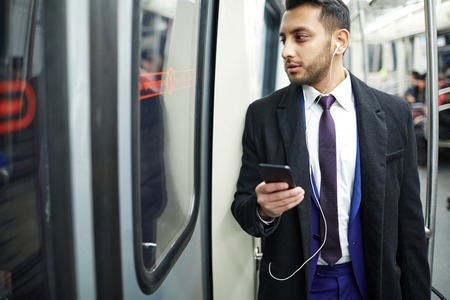 Elegant businessman with smartphone going by metroの写真素材