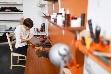 Young tanner working with leather pieces in his workroomの写真素材