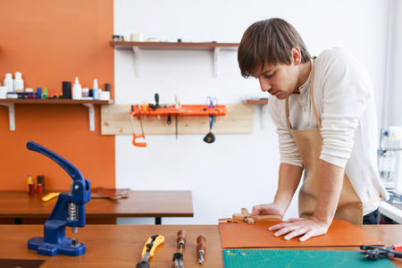 Tanner cutting piece of leather in workshop