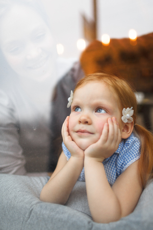 Peaceful girl daydreaming while looking through windowの写真素材