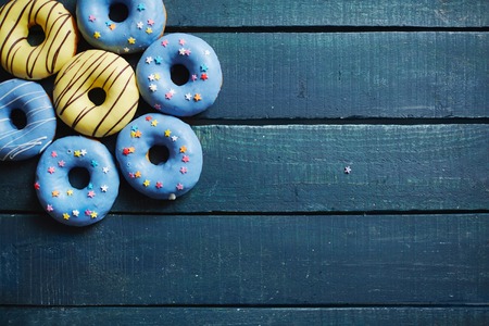 Blue wooden boards with group of tasty donuts on topの写真素材