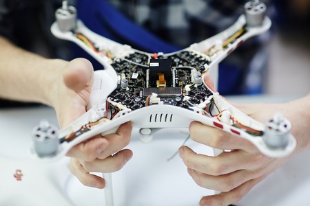 Closeup shot of male hands holding opened drone showing main circuit board and micro controller unit...