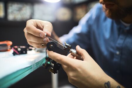 Tattoo master preparing machine for workの写真素材