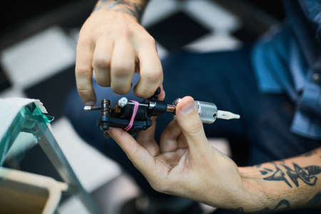 Hands of master holding tattoo-machineの写真素材