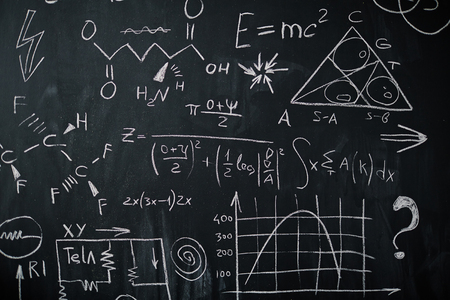 Background shot of blackboard with scientific and algebraic formulas and graphs written on it in chalkの写真素材