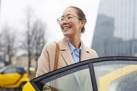 Asian Businesswoman Taking Taxi in Rainy Streetの写真素材