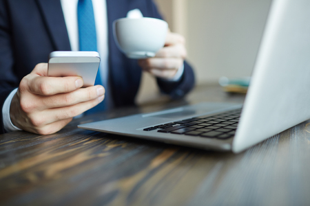 Elegant Businessman Using Smartphone in Cafeの写真素材