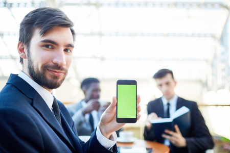 Confident Businessman Presenting Mobile Appの写真素材