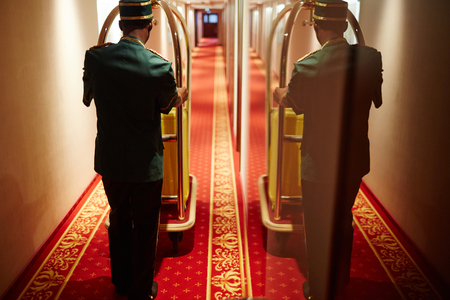 Bellboy Pushing Luggage Cart in Hotel Hallway