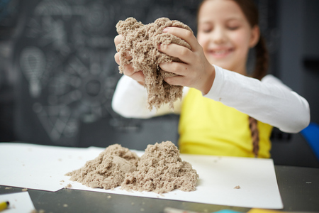 Happy Little Girl Playing with Kinetic Sand at Daycare Centerの写真素材