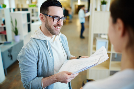 Smiling Man Discussing Documents with Colleagueの写真素材