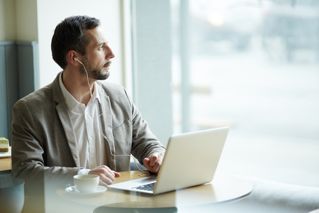 Pensive mature Man Using Laptop in Cafeの写真素材