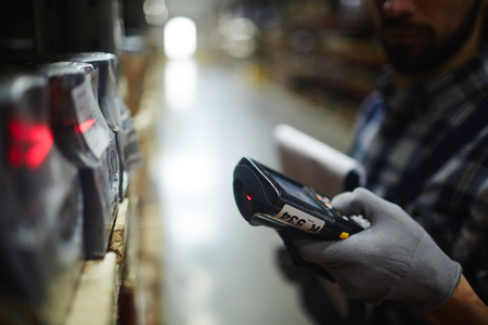 Side view closeup of bar code scanner in hand of unrecognizable warehouse worker doing inventory of stockの写真素材