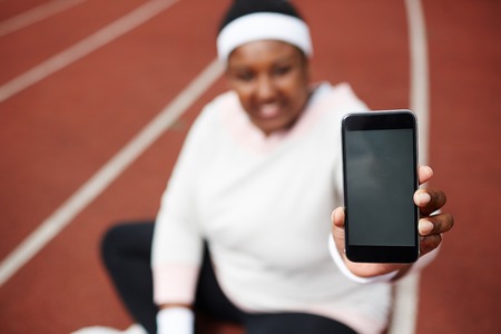 Defocused African overweight woman showing screen of her black smartphoneの写真素材
