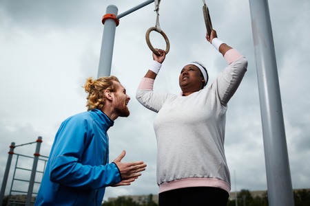 Experienced personal trainer motivating plus-size female to exerciseの写真素材