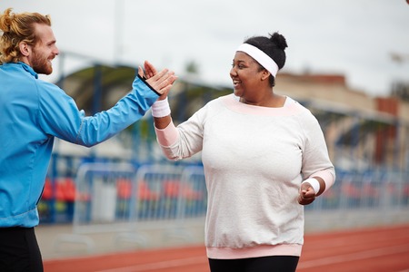 Happy plus-size woman giving high five to her personal trainerの写真素材