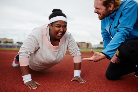 Fat woman doing push ups motivated by personal coachの写真素材