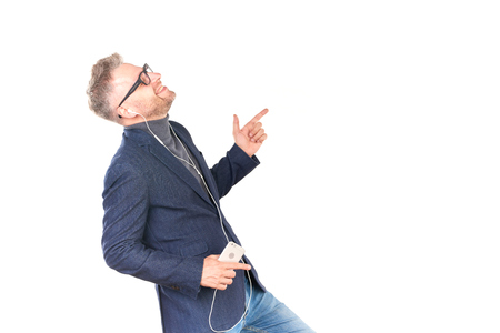 Middle adult man in eyeglasses listening to music on smartphone through earphonesの写真素材