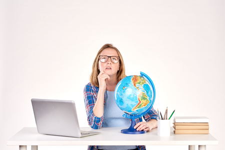 Portrait of female student sitting at desk and using globeの写真素材