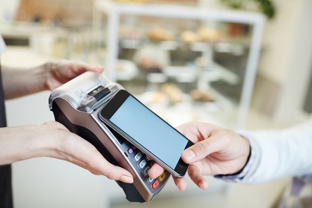 Contemporary client of cafe making contactless payment after lunch