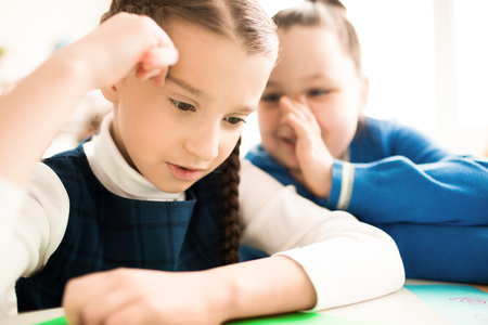 Little girl tells the story to the neighbor at the table at lessonの写真素材