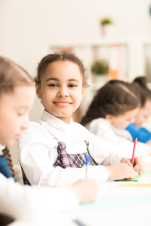 Group of students working at school classroom with schoolgirl smiling at cameraの写真素材