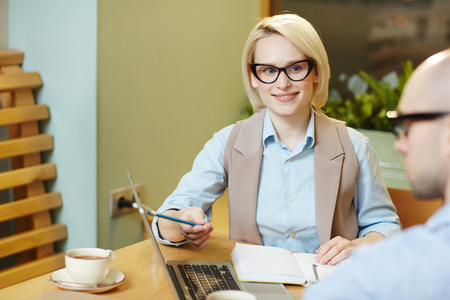 Young businesswoman pointing at computer screen and working with businessman in teamの写真素材