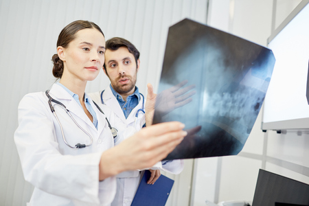 Team of surgeons examining x-ray image togetherの写真素材