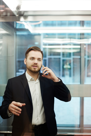 Young businessman in suit talking on the phone in modern office