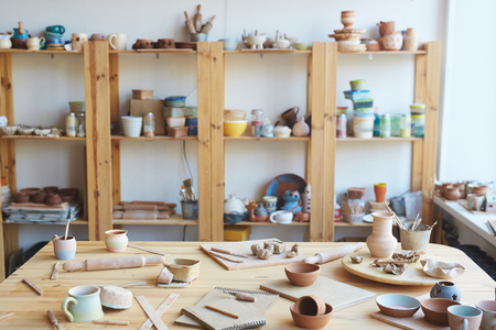 Messy workshop with handmade clay vases, pots and jars made by professional potterの写真素材