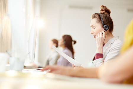 Businesswoman in headset communicating with client in call centerの写真素材