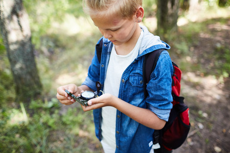Young scout finding way using compassの写真素材