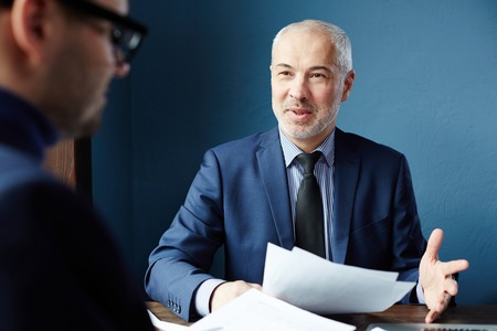 Mature businessman having an interview with man. He is communicating about workの写真素材