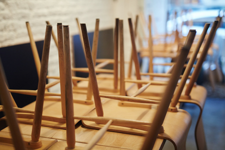 Close-up view of wooden chairs stacked upside down on table in closed restaurantの写真素材