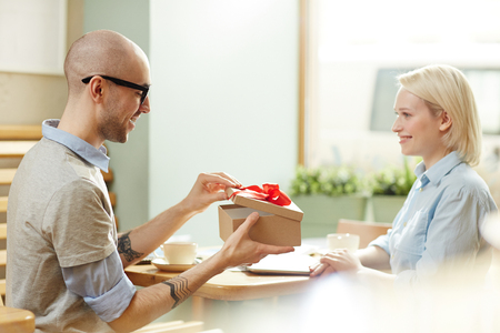 Smiling man giving gift giving by womanの写真素材