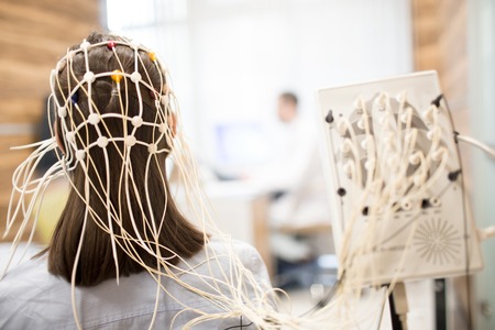 Rear view of girl with eeg electrode equipment on her head having medical testの素材 [FY310102304979]