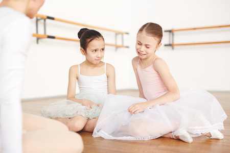 Little sad ballerinas sitting on floor in studioの写真素材